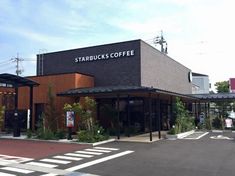 a starbucks coffee shop sitting on the side of a road next to a cross walk