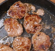 hamburger patties being cooked in a skillet on a wooden counter top with oil