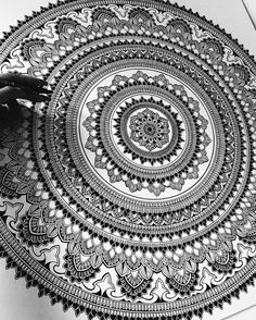 someone is drawing an intricately detailed design on white paper with black marker and pen