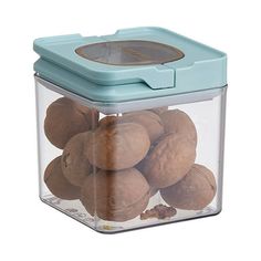 a glass container filled with nuts sitting on top of a white table next to a blue lid