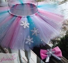 a pink, blue and white tutu with snowflakes on the top is sitting next to a window sill