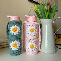 three crocheted water bottles sitting next to each other on top of a table