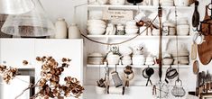 a kitchen with lots of pots and pans hanging from the wall next to a white refrigerator