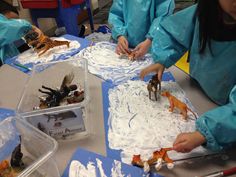 two girls in blue coats are playing with plastic animals