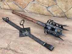 two old fashioned swords are sitting next to each other on a wooden table with a stone wall behind them