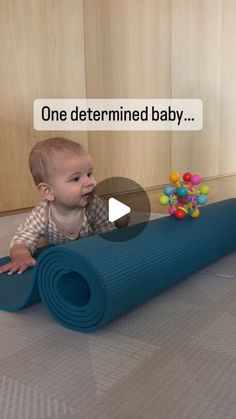 a baby laying on the floor next to a blue mat with gumballs in it