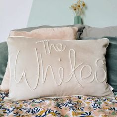 a pillow that says the whick is on top of a bed with floral sheets