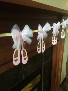 pink and white baby shower decorations hanging from a fireplace mantel in a living room