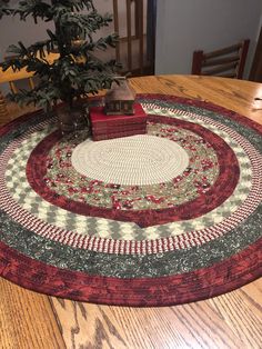 a christmas tree sits on top of a round tablecloth with a small house in the center