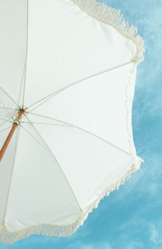 an umbrella with fringed edges against a blue sky