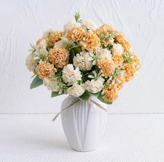 a white vase filled with orange and white flowers