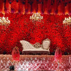 a white couch sitting in front of a red wall with chandeliers hanging from it