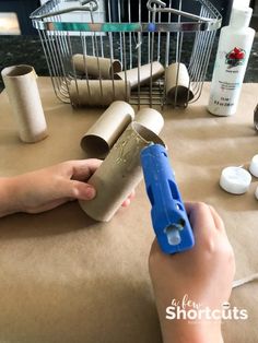 a person is making toilet paper rolls with a blue plastic tube and some other items