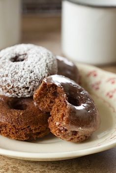 three donuts are on a plate with coffee in the background