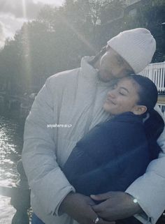 a man and woman hugging each other by the water