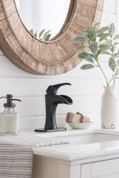 a bathroom sink with a black faucet under a round mirror