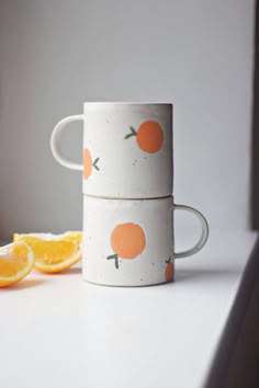 two cups with oranges painted on them