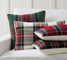 pillows and blankets on a white couch with plaid pattern in the back, side by side