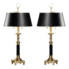 a pair of black and gold table lamps with shades on each lamp, one is turned off