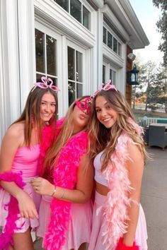 three girls dressed in pink posing for the camera outside a building with their arms around each other