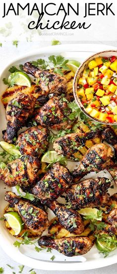 grilled chicken and vegetables on a white platter with a bowl of mango salsa