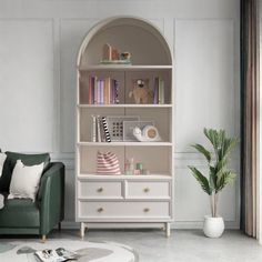 a living room with a green couch and white bookcase on the wall next to a potted plant