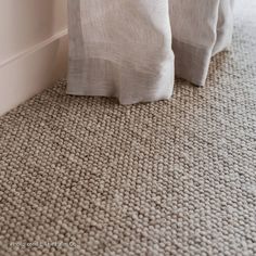 two white pillows sitting on top of a bed next to a wall and carpeted floor