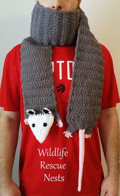 a man wearing a knitted scarf with two raccoons attached to the neck