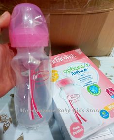 someone is holding a pink baby bottle next to its packaging