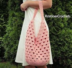 a woman is holding a pink crocheted bag in front of some bushes and trees