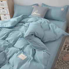 an unmade bed with blue sheets and pillows