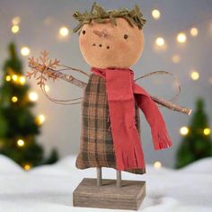 a wooden doll with a red scarf on it's head holding a snowflake