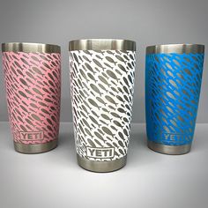 three different colored yeti cups sitting next to each other on a white table top