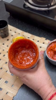 a person holding a bowl of sauce in their hand