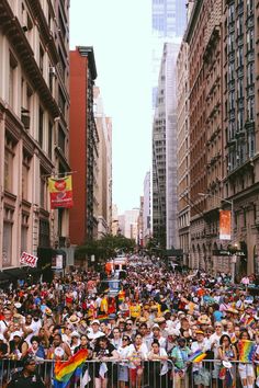 a large group of people standing in the middle of a street next to tall buildings