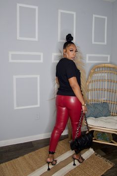 a woman in red leather pants standing next to a wicker chair and ratchet