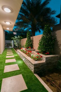 an outdoor garden with artificial grass and stone planters on either side of the walkway