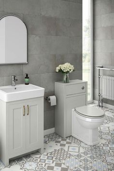 a white toilet sitting next to a sink in a bathroom under a mirror and a radiator