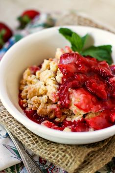 a close up of a bowl of food with strawberries in it on a table