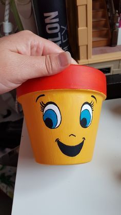 a hand is holding a cup with a face painted on it