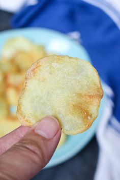 a person holding up a piece of food in front of a plate with potatoes on it