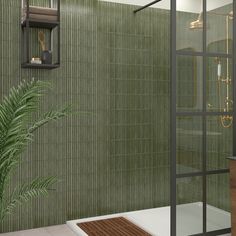 a green tiled bathroom with a plant in the corner and a glass shower door on the side