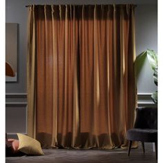 a person laying on the floor in front of a window with brown curtains and pillows