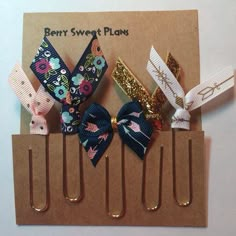 four small hair clips with bows in them on top of a piece of brown paper