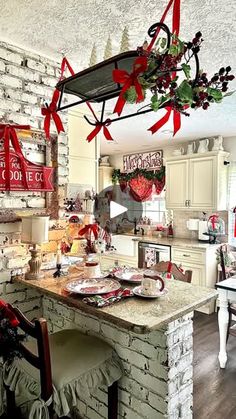 the kitchen is decorated for christmas with red bows and decorations hanging from the ceiling over the island