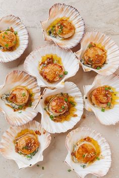 several scallops with sauce and green onions in them sitting on a table top