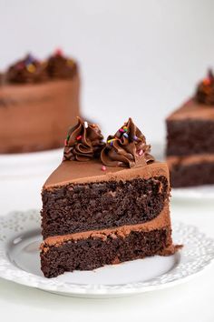 a slice of chocolate cake on a white plate with sprinkles and chocolate frosting