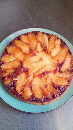 a pineapple upside down cake on a blue plate sitting on a gray counter top