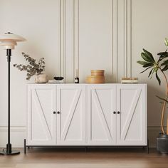 a white cabinet sitting next to a lamp on top of a hard wood floor