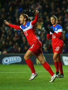 two female soccer players are celebrating their team's victory over the other team in a game